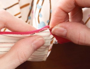 hand stitching the edges of the zip