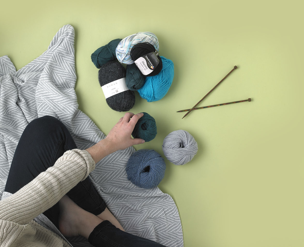 Green and blue colour yarn skeins with a set of knitting needles