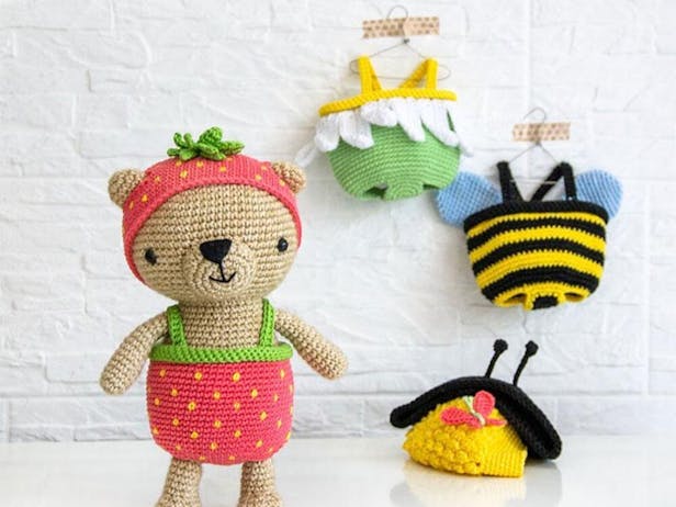 Crochet teddy bear wearing a strawberry hat