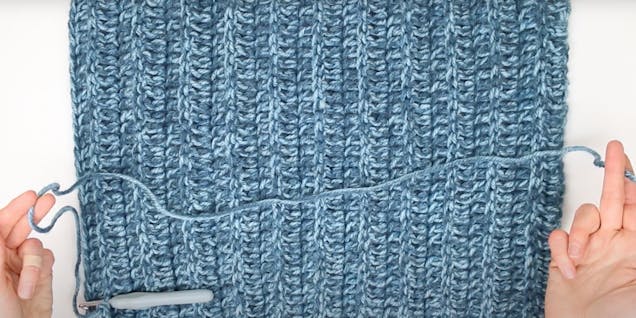 flat lay of crocheted square with long yarn tail ready to sew