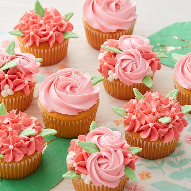 Cupcakes decorated with pink and coral piped flowers