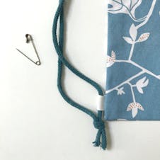 Cord handle fastened in knot and secured to the bag with ribbon loop