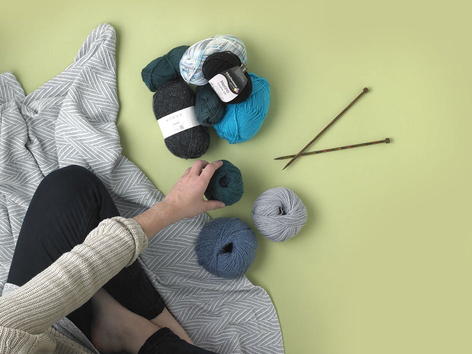 Green and blue colour yarn skeins with a set of knitting needles